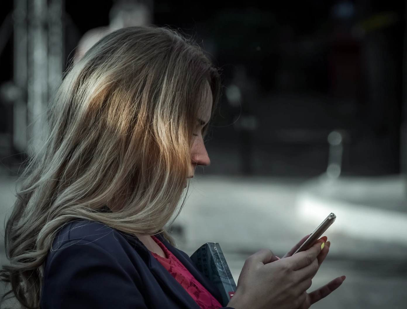 Woman looking at her phone on a city street in the evening