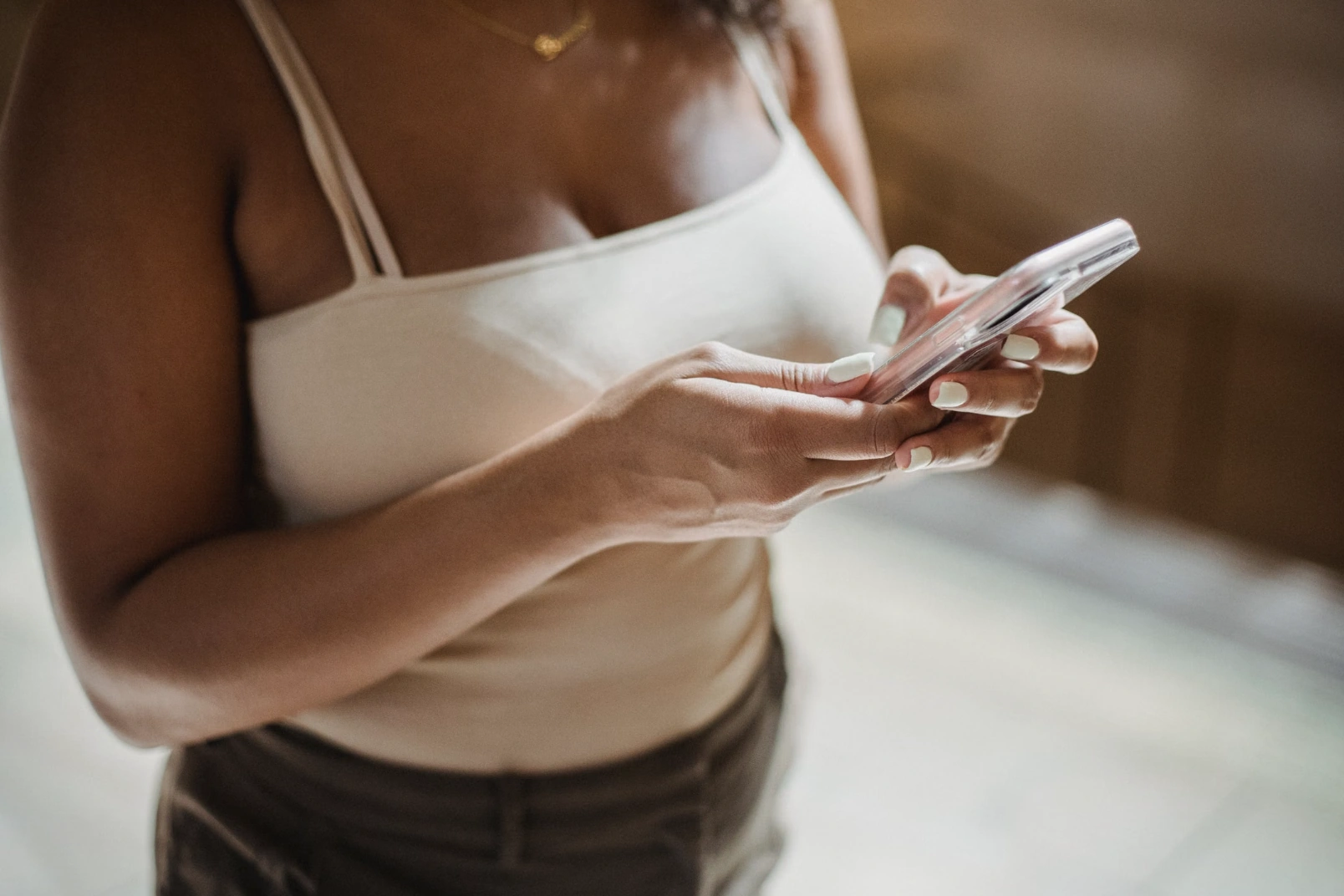 Close-up of a woman in a white top holding a phone in her hands