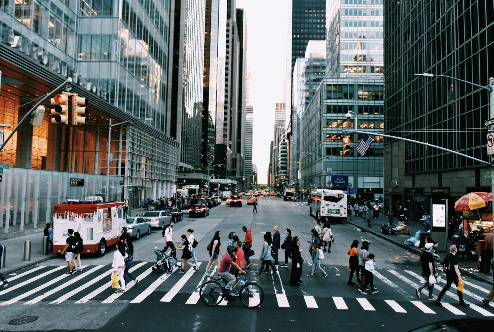 People crossing a busy city street lined with skyscrapers